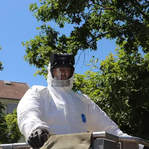 Mitarbeiter der Fachfirma in Überdruck-Schutzanzug, Atemmaske und Gummihandschuhen.