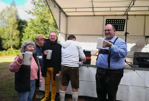 Vier Personen mit Bierkrug, ein Mann zapft vom Fass in der Mitte.