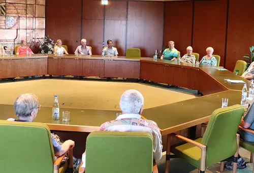 Menschen sitzen um an Tischen, die in einem Achteck ausgerichtet sind.