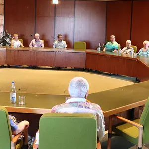 Menschen sitzen um an Tischen, die in einem Achteck ausgerichtet sind.