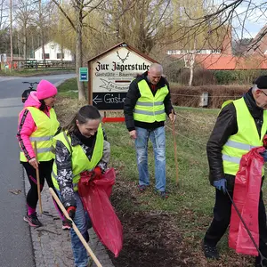 Zwei Frauen und zwei Männer sammeln Abfall am Straßenrand