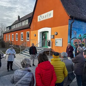 Mann in der Mitte spricht und das Publikum hört stehend zu.