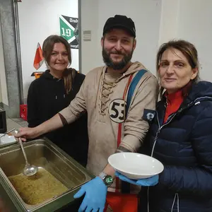 Zwei Frauen und ein Mann bei der Essensausgabe