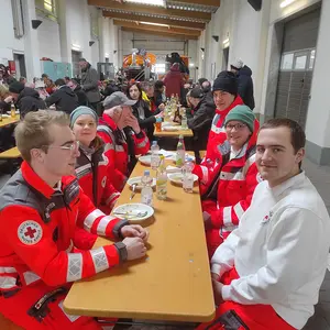 Mitglieder des BRK in ihren Uniformjacken am Tisch im Bauhof