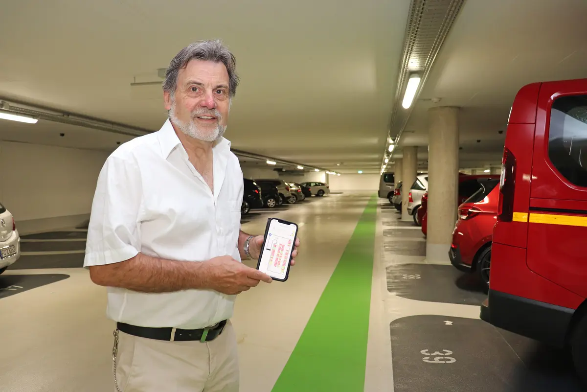 Ein Mann präsentiert in der Tiefgarage die App auf seinem Mobiltelefon.