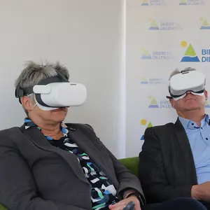 Ein Mann und eine Frau mit der VR-Brille auf einen grünen Sofa.