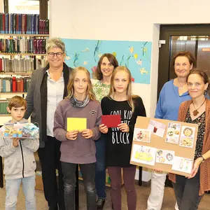 Gruppenbild mit vier FRauen im HIntergrund und drei Kindern im Vordergrund mit ihren Preisen.