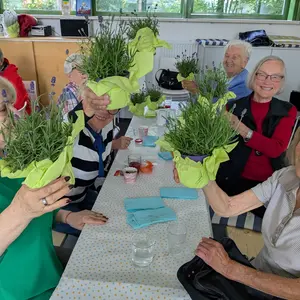 Senior:innen halten fröhlich Lavendelstöckchen Richtung Kamera 