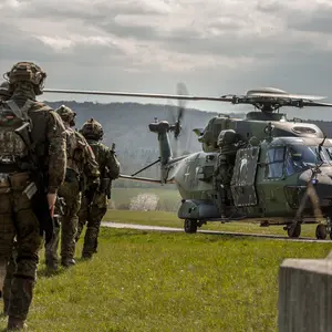 Soldaten in Flecktarn laufen auf einen Hubschrauber zu