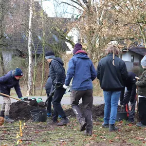 Kinder mit Schaufeln in der Hand füllen einen Eimer mit Erde. Ein Junge rennt durchs Bild. 