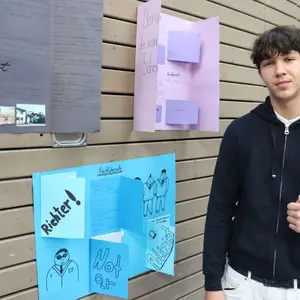 Junge neben Din A2-Plakaten 