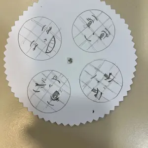 Eine gezackte Papierscheibe, auf der vier Gesichter gezeichnet sind. 
