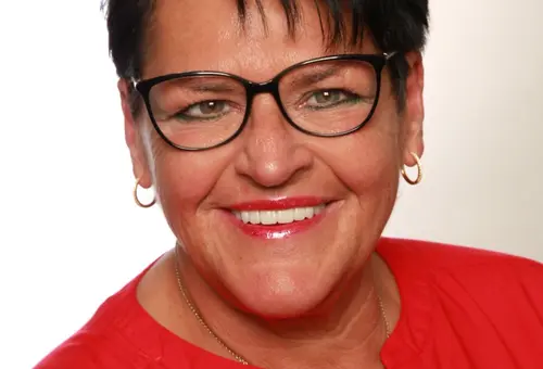 Frau mit kurzen dunklen Haaren und Brille und roter Bluse
