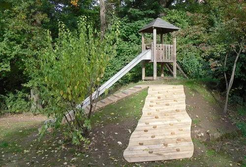 Hügel mit Rutschenturm und hölzernen Kletteraufstiegen.