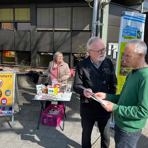 Zwei Männer im Gespräch, im Hintergrund eine Frau