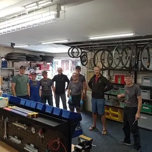 Acht Männer stehen in einer Fahrradwerkstatt