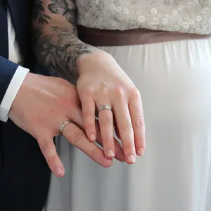 Nachdem die Trauung vollzogen ist, zeigt das Brautpaar ihre Trauringe