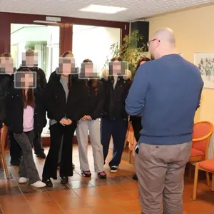 Lehrerin, Schüler:innen und die beiden Leiter:innen des Heims. 