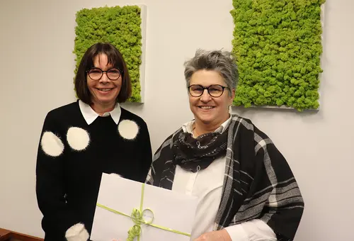 Zwei Frau halten einen Geschenkumschlag vor sich.