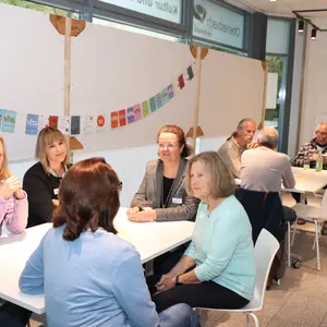 Personen an mehreren Tischen 