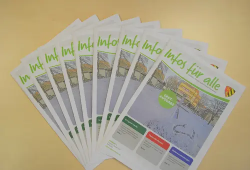 Mehrere Mitteilungsblätter liegen aufgefächert auf dem Tisch.